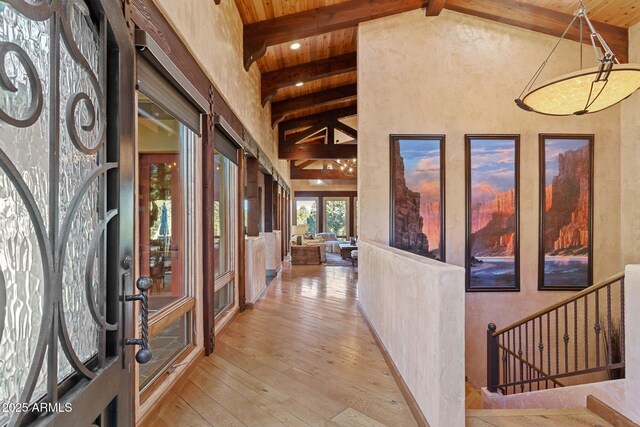 corridor featuring light wood-type flooring, wooden ceiling, and lofted ceiling with beams