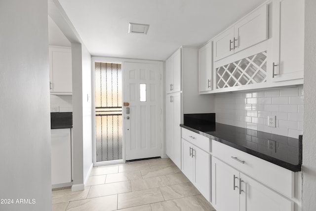 kitchen featuring light tile patterned floors, backsplash, and white cabinetry