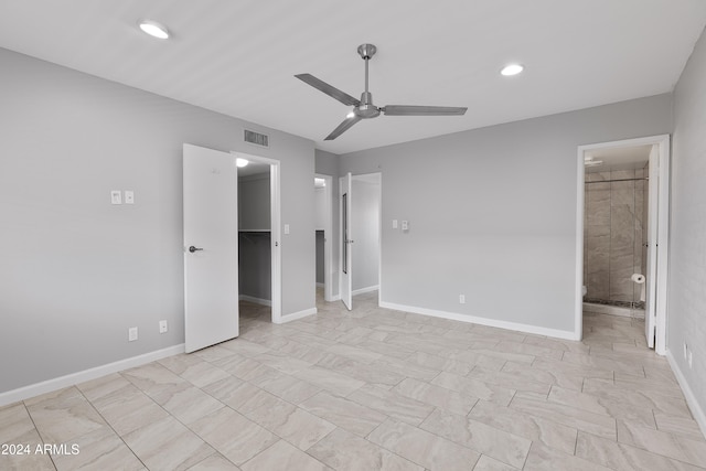 unfurnished bedroom featuring a walk in closet, a closet, ensuite bath, and ceiling fan