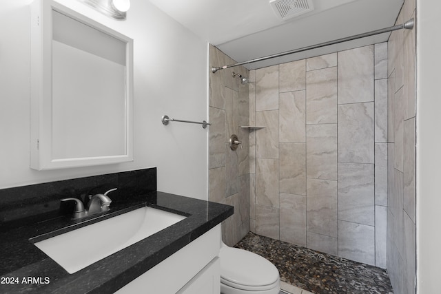 bathroom featuring vanity, toilet, and tiled shower