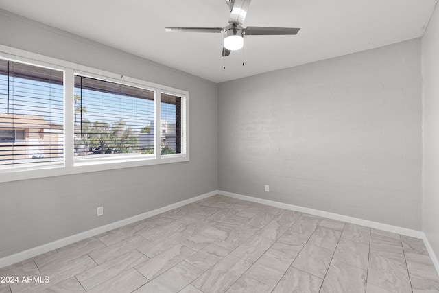 unfurnished room with ceiling fan and brick wall