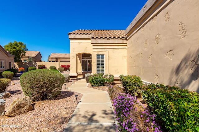 exterior space featuring a tile roof, fence, and stucco siding