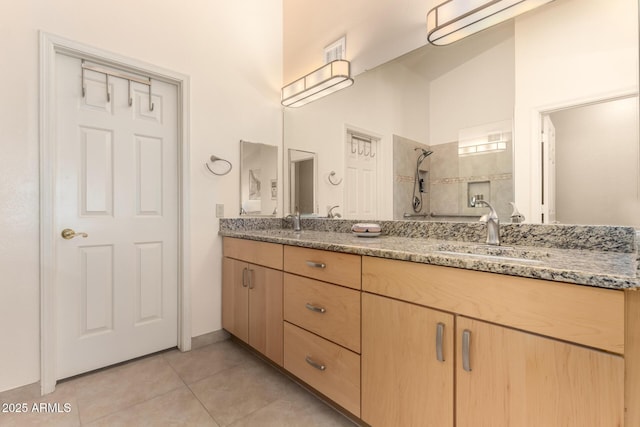 full bath featuring a sink, tiled shower, double vanity, and tile patterned flooring