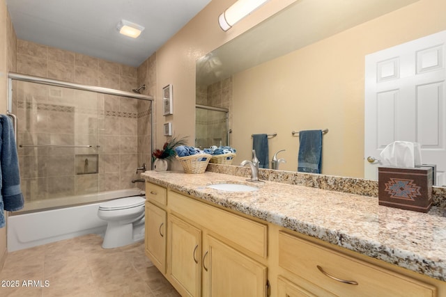 bathroom featuring tile patterned floors, toilet, vanity, and shower / bath combination with glass door