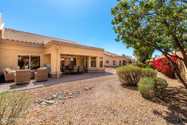 rear view of property featuring an outdoor living space, a tile roof, stucco siding, a patio area, and a ceiling fan