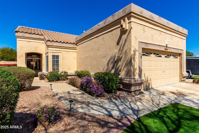 view of home's exterior with stucco siding, driveway, an attached garage, and a tiled roof