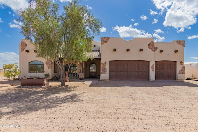 southwest-style home with a tile roof, driveway, an attached garage, and stucco siding