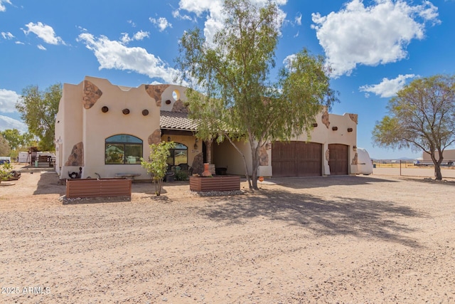 southwest-style home with a garage, driveway, and stucco siding