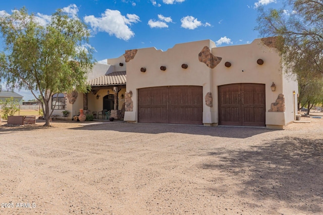 southwest-style home with driveway, a garage, and stucco siding