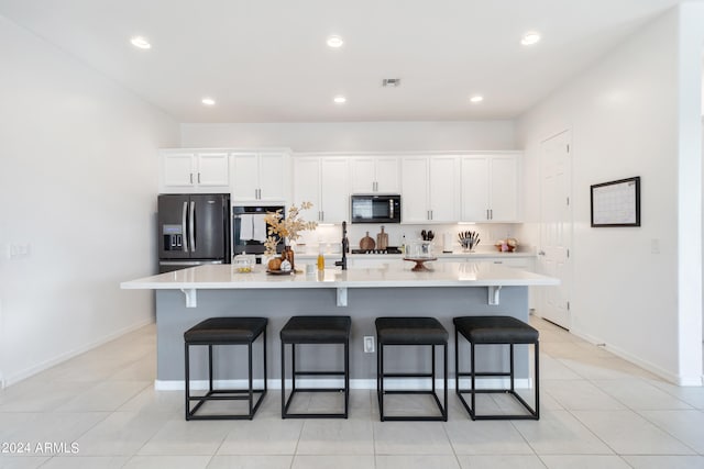 kitchen featuring a large island, stainless steel appliances, a kitchen breakfast bar, and white cabinets