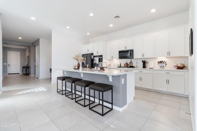 kitchen featuring a center island with sink, a breakfast bar, appliances with stainless steel finishes, and white cabinets