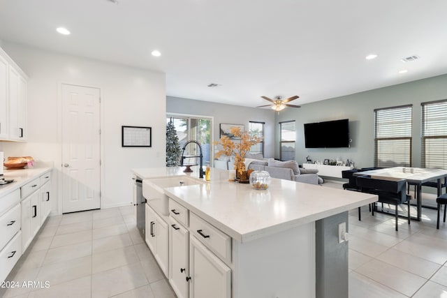 kitchen with white cabinets, a center island with sink, stainless steel dishwasher, light tile patterned flooring, and sink