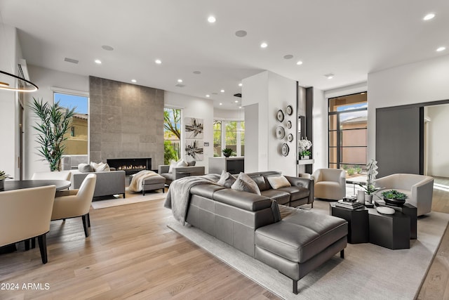 living room with a healthy amount of sunlight, light hardwood / wood-style flooring, and a tile fireplace