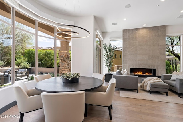 dining space featuring a fireplace, light hardwood / wood-style floors, and a wealth of natural light