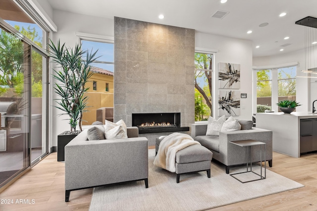 living room with sink, a tile fireplace, and light wood-type flooring