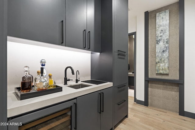 bar featuring sink, beverage cooler, gray cabinets, and light hardwood / wood-style flooring