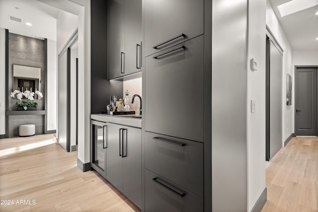 kitchen featuring sink, a skylight, light hardwood / wood-style flooring, and gray cabinets