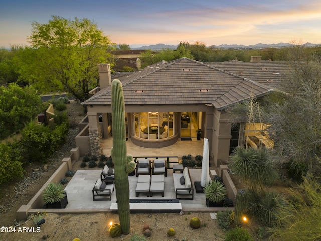 back house at dusk with a patio area and outdoor lounge area