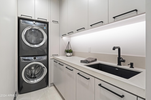 washroom with cabinets, light tile patterned floors, stacked washer and clothes dryer, and sink