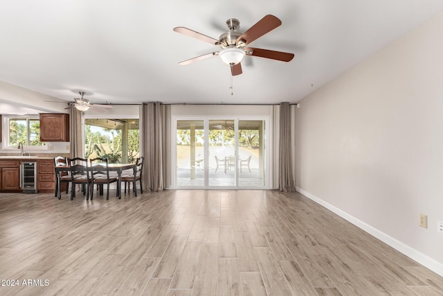 interior space with light hardwood / wood-style flooring, a wealth of natural light, beverage cooler, and ceiling fan