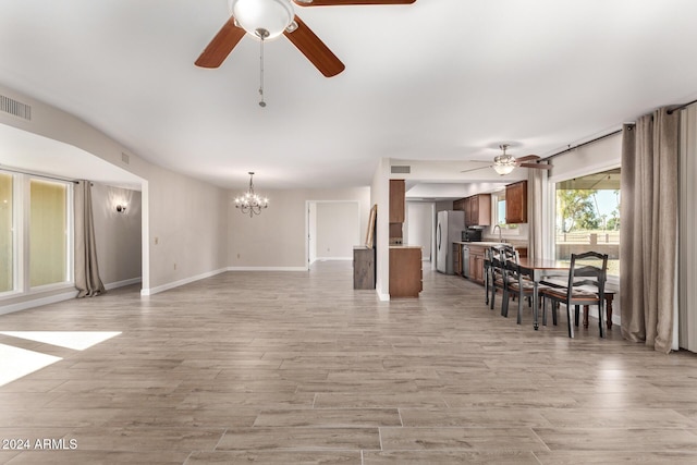 living room with ceiling fan with notable chandelier and light hardwood / wood-style floors