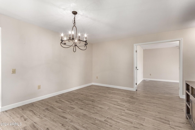 unfurnished room featuring light hardwood / wood-style floors and an inviting chandelier