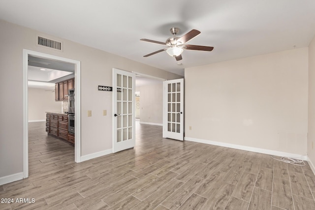 empty room featuring ceiling fan, french doors, and light hardwood / wood-style floors