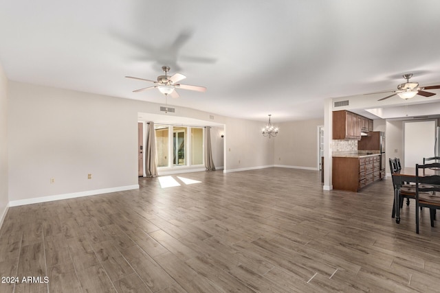 unfurnished living room featuring ceiling fan with notable chandelier and dark hardwood / wood-style floors