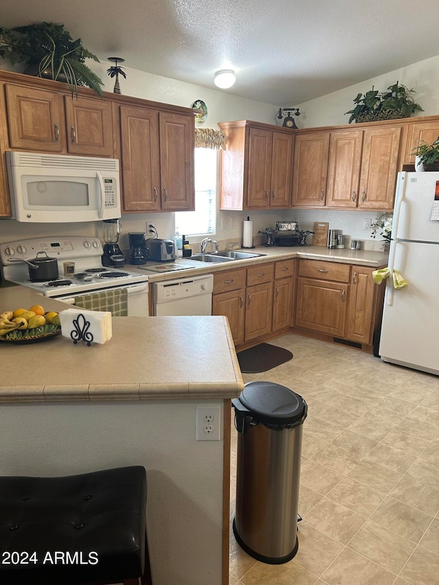 kitchen with white appliances, a textured ceiling, and sink