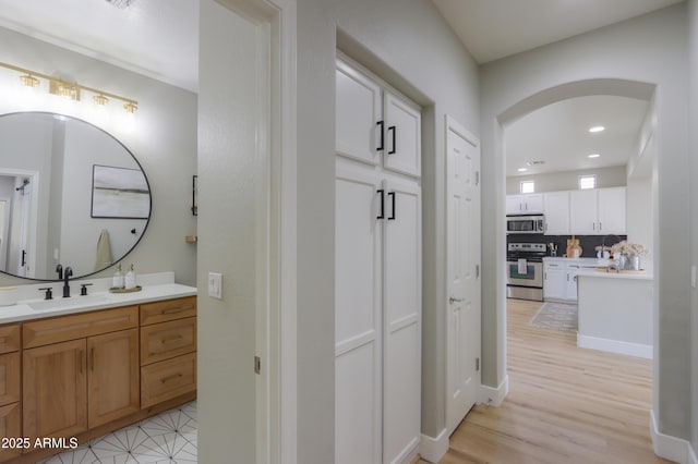 bathroom with recessed lighting, vanity, decorative backsplash, and wood finished floors