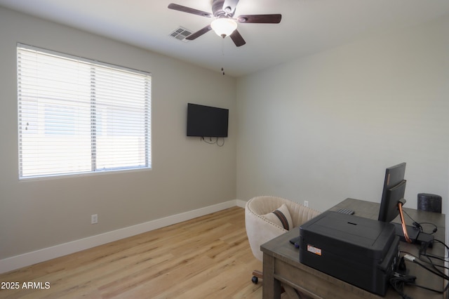 office space featuring baseboards, light wood-style flooring, visible vents, and a ceiling fan