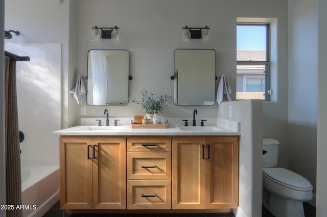 bathroom with toilet, double vanity, and a sink