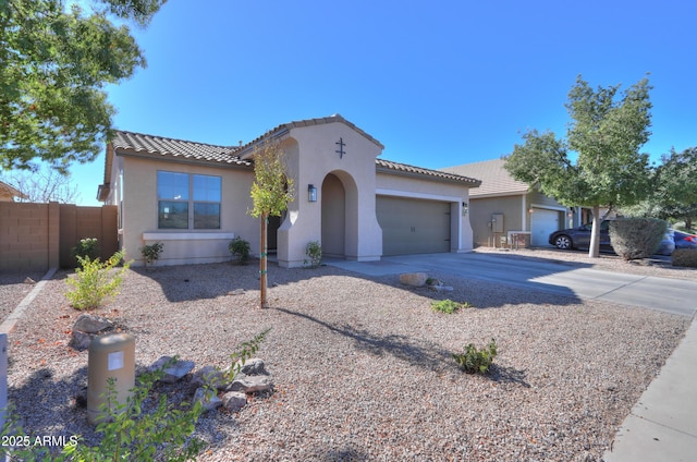 mediterranean / spanish house featuring a garage, driveway, fence, and stucco siding