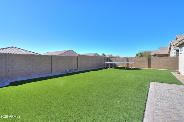 view of yard featuring a fenced backyard and a trampoline