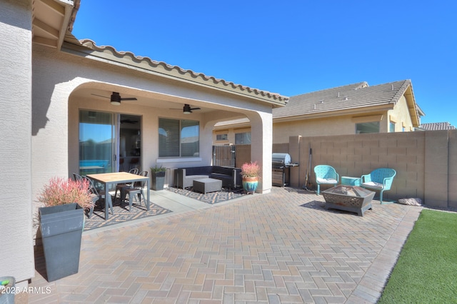 view of patio featuring an outdoor fire pit, outdoor dining area, fence, and a ceiling fan