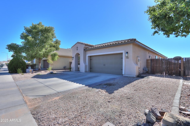 mediterranean / spanish home featuring a garage, fence, a tile roof, driveway, and stucco siding