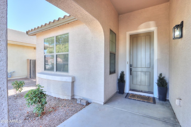 view of exterior entry featuring a tiled roof and stucco siding