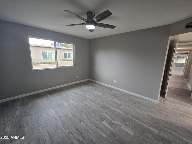 empty room featuring ceiling fan, baseboards, and wood finished floors