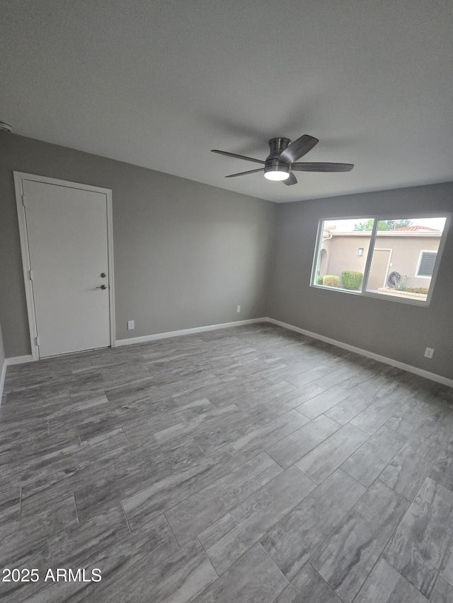 empty room featuring dark wood finished floors, ceiling fan, and baseboards