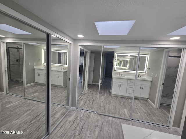 bathroom with two vanities, a sink, and wood finished floors