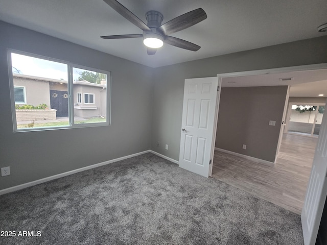 unfurnished bedroom with carpet floors, baseboards, a ceiling fan, and wood finished floors