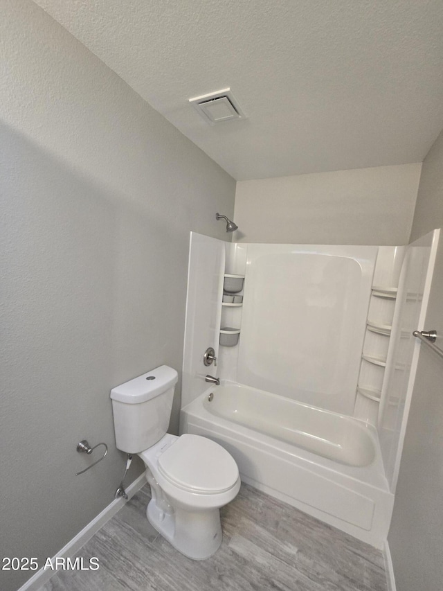 full bath featuring a textured ceiling, toilet, wood finished floors, bathing tub / shower combination, and visible vents