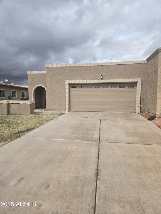 view of front of house with a garage, concrete driveway, and stucco siding