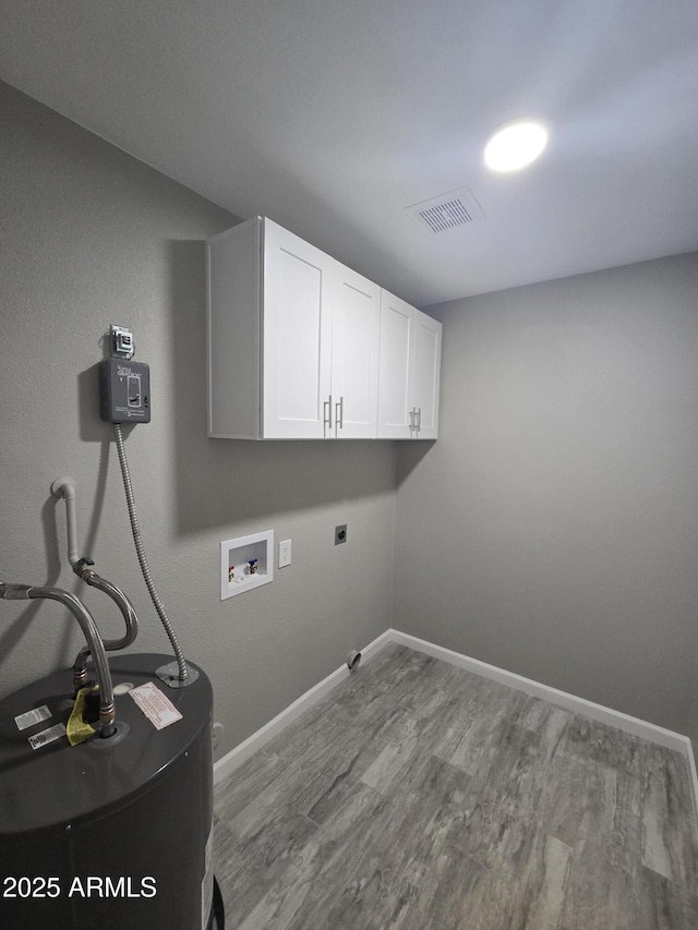 washroom with hookup for a washing machine, cabinet space, visible vents, water heater, and wood finished floors