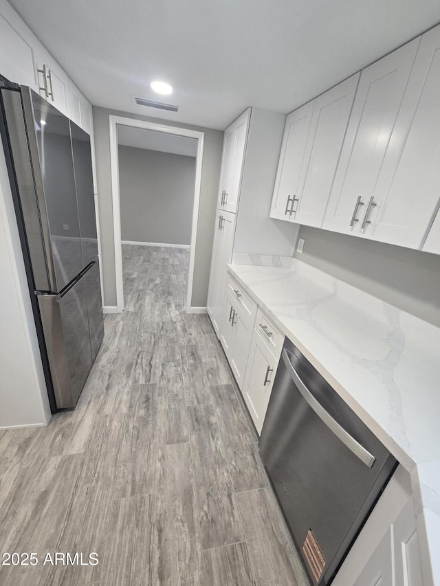 kitchen featuring visible vents, light stone counters, stainless steel appliances, light wood-type flooring, and white cabinetry