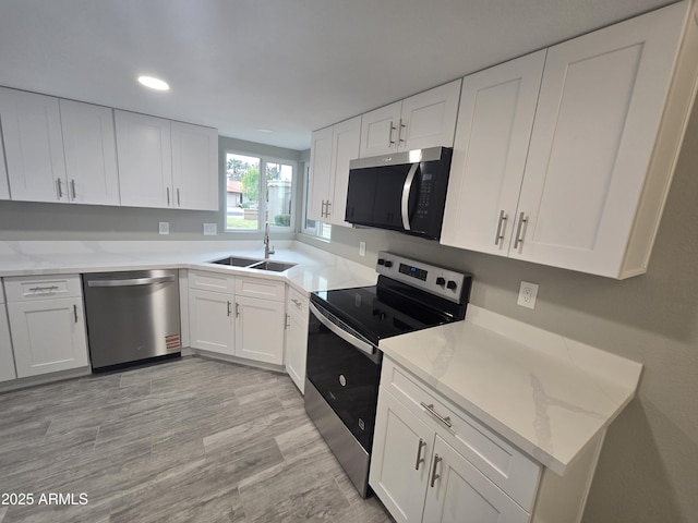 kitchen featuring recessed lighting, a sink, white cabinetry, appliances with stainless steel finishes, and light stone countertops