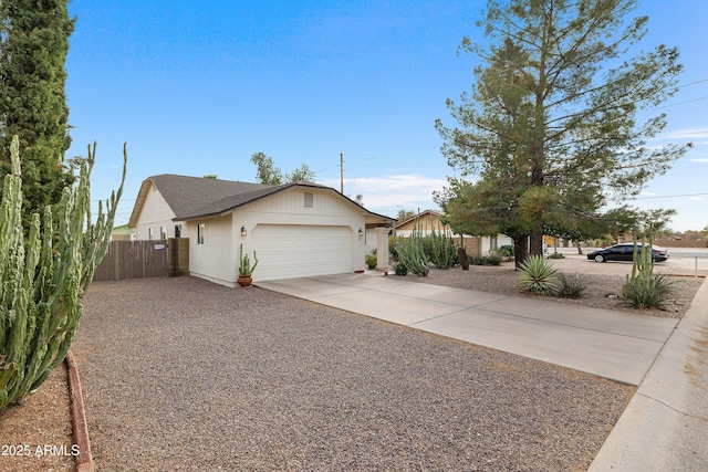 view of side of property featuring concrete driveway, a garage, and fence