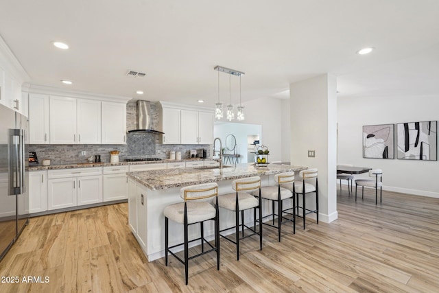 4920 E Osborn Rd, Phoenix, AZ 85018 - kitchen with wall chimney range hood, gas cooktop, high end fridge, tasteful backsplash, and a kitchen breakfast bar