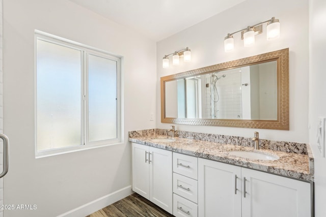4920 E Osborn Rd, Phoenix, AZ 85018 - bathroom featuring double vanity, a tile shower, wood finished floors, and baseboards