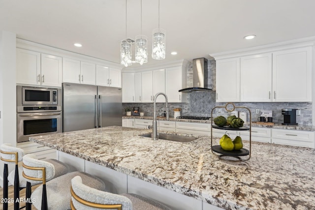 4920 E Osborn Rd, Phoenix, AZ 85018 - kitchen featuring stainless steel appliances, wall chimney range hood, a sink, a breakfast bar, and white cabinets